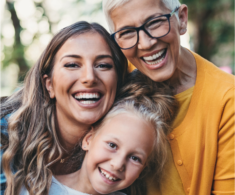 Mom, child, and grandparent smiling at the camera